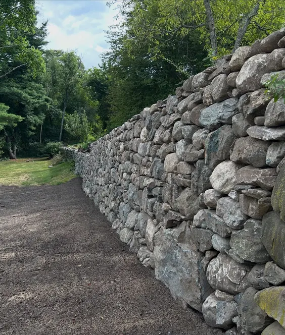 Natural boulder retaining wall along a driveway