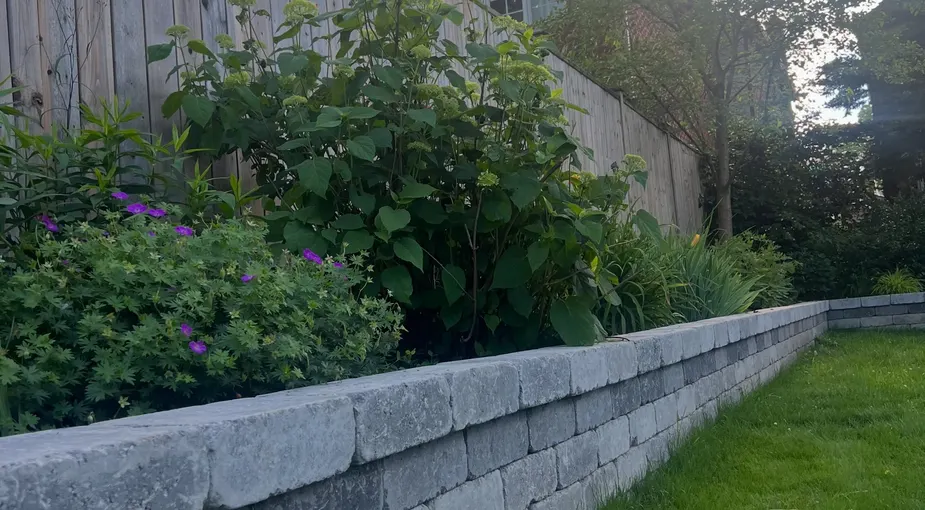 Dark stacked stone garden wall with a flat stone cap