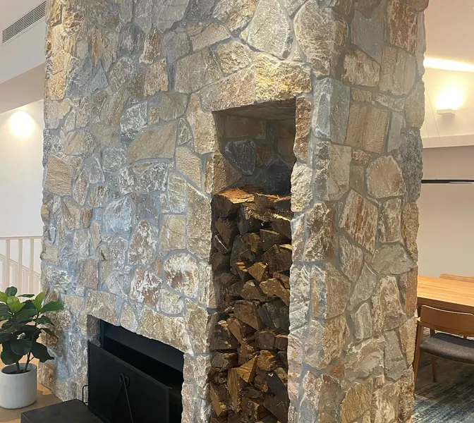 Natural fieldstone fireplace with built-in wood storage