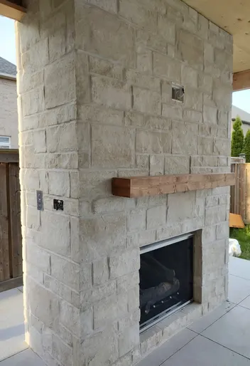 Outdoor limestone fireplace on a covered patio
