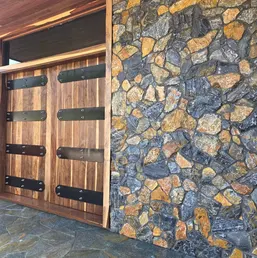 Fieldstone Veneer Wall Beside Wood Garage Doors, photo 1