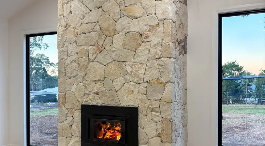 Stone fireplace installation with a natural fieldstone surround and wood mantel