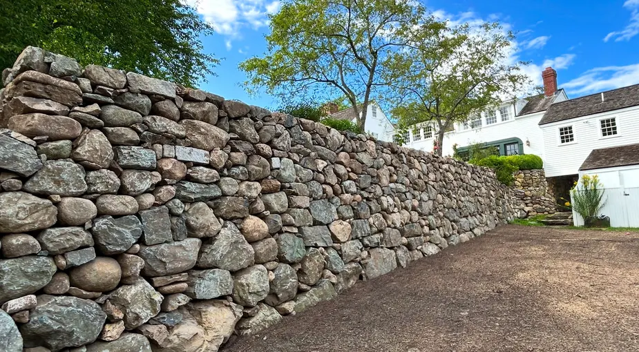 Natural boulder stone retaining wall holding back a sloped yard