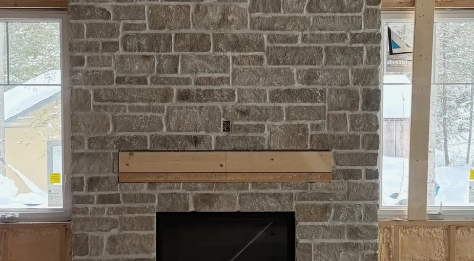 Stone veneer repair work on a stone fireplace chimney under construction