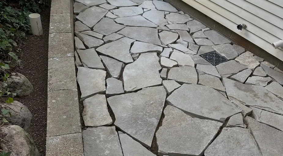 Natural flagstone walkway installation along the side of a house
